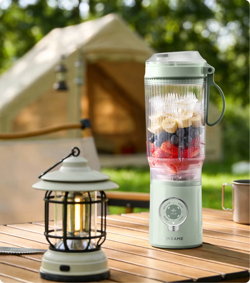 Dreame Portable Blender kabelloses Design auf einem Picknicktisch beim Mixen von Fruchtgetränken im Freien am Wasser