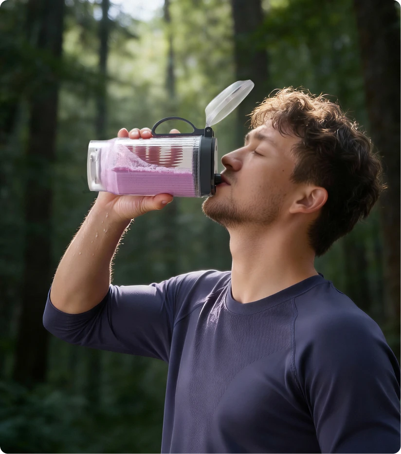 Nutzer trinkt einen Smoothie aus dem tragbaren Dreame Portable Blender Becher bei einer Wanderung im Wald