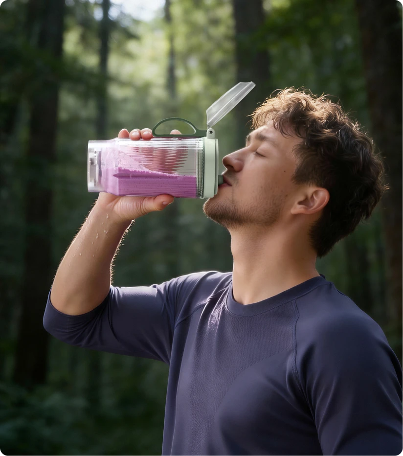 Nutzer trinkt einen Smoothie aus dem tragbaren Dreame Portable Blender Becher bei einer Wanderung im Wald