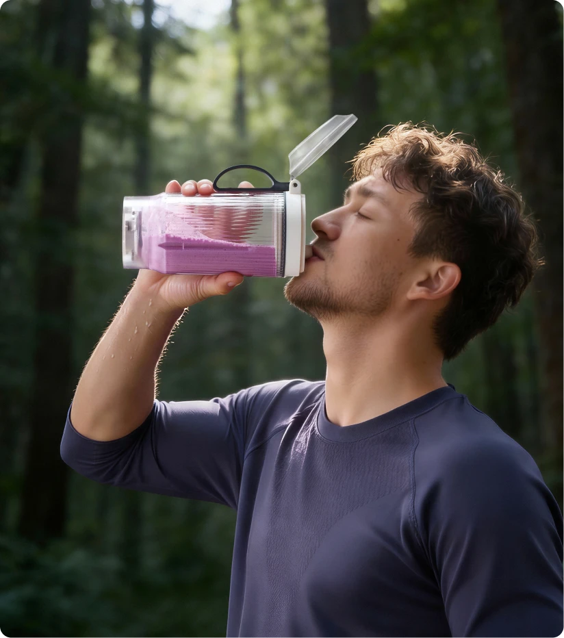 Nutzer trinkt einen Smoothie aus dem tragbaren Dreame Portable Blender Becher bei einer Wanderung im Wald