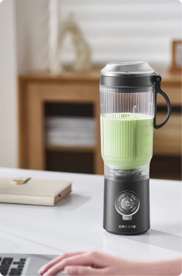 Dreame Portable Blender kabelloses Design auf einem Schreibtisch im Büro beim Mixen eines grünen Getränks