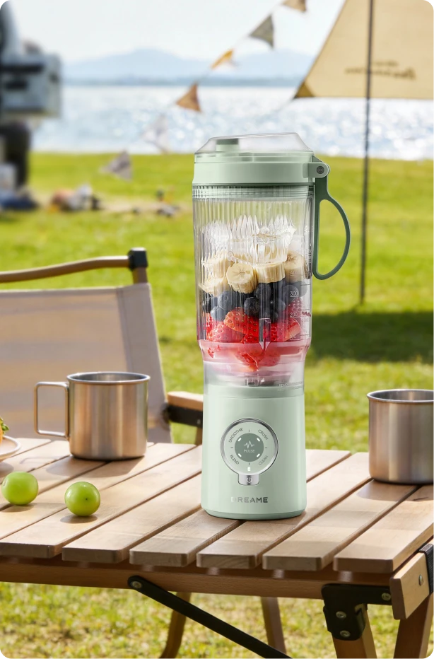 Dreame Portable Blender kabelloses Design auf einem Picknicktisch beim Mixen von Fruchtgetränken im Freien am Wasser
